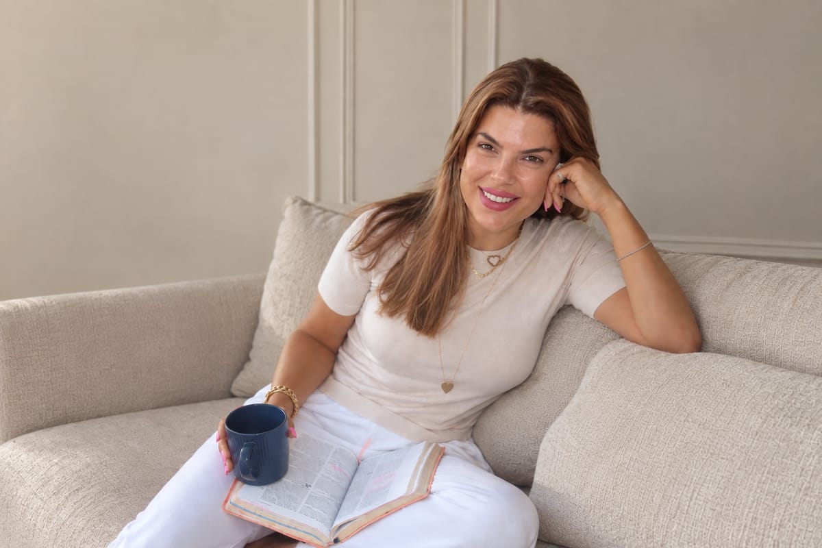 Shahera on a sofa with a mug and an open Bible on her lap.